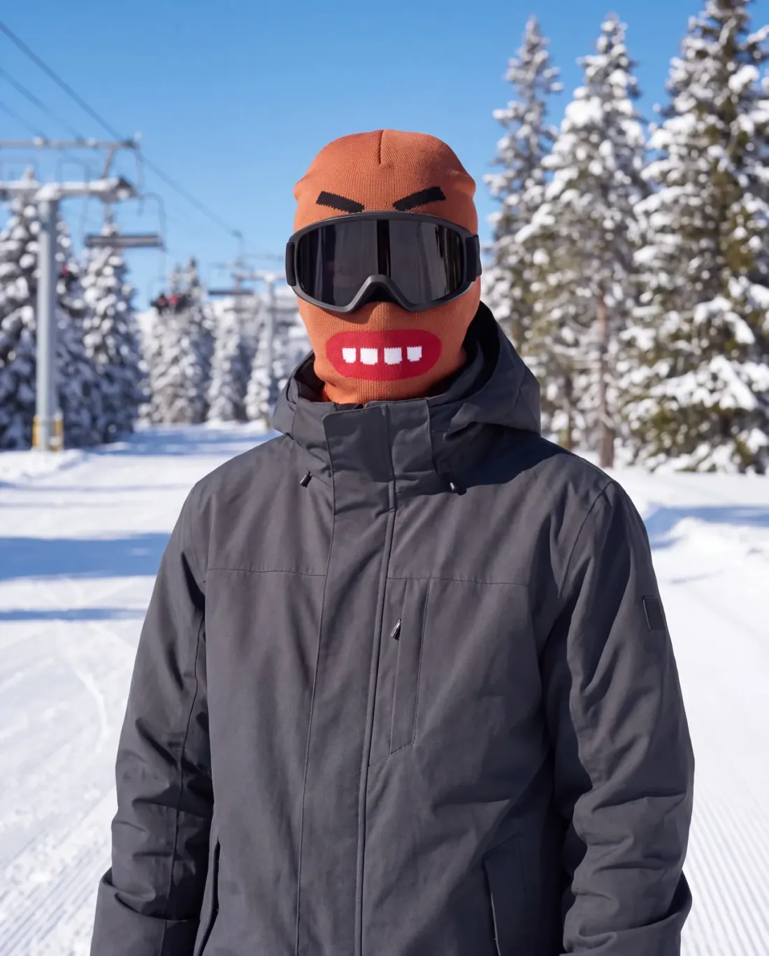 Ella R. wearing the CHOMP noggos. character ski mask on a chairlift